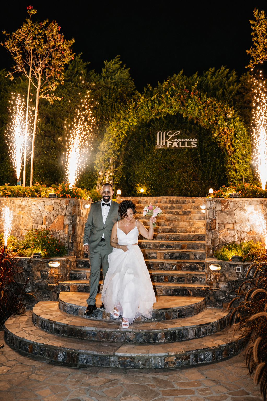 Bride and groom celebrate on the stone-built garden levels at night with pyrotechnics